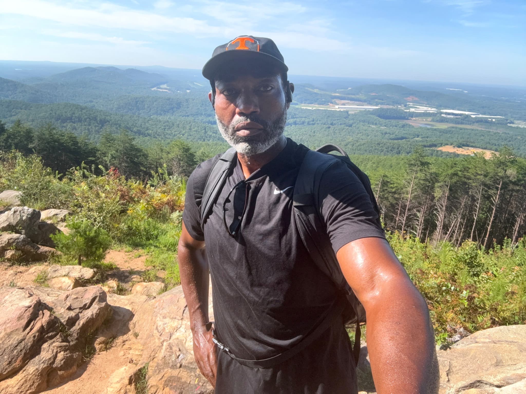 Chad Everett Shaw at a mountain overlook wearing a Tennessee cap, black shirt, and backpack.